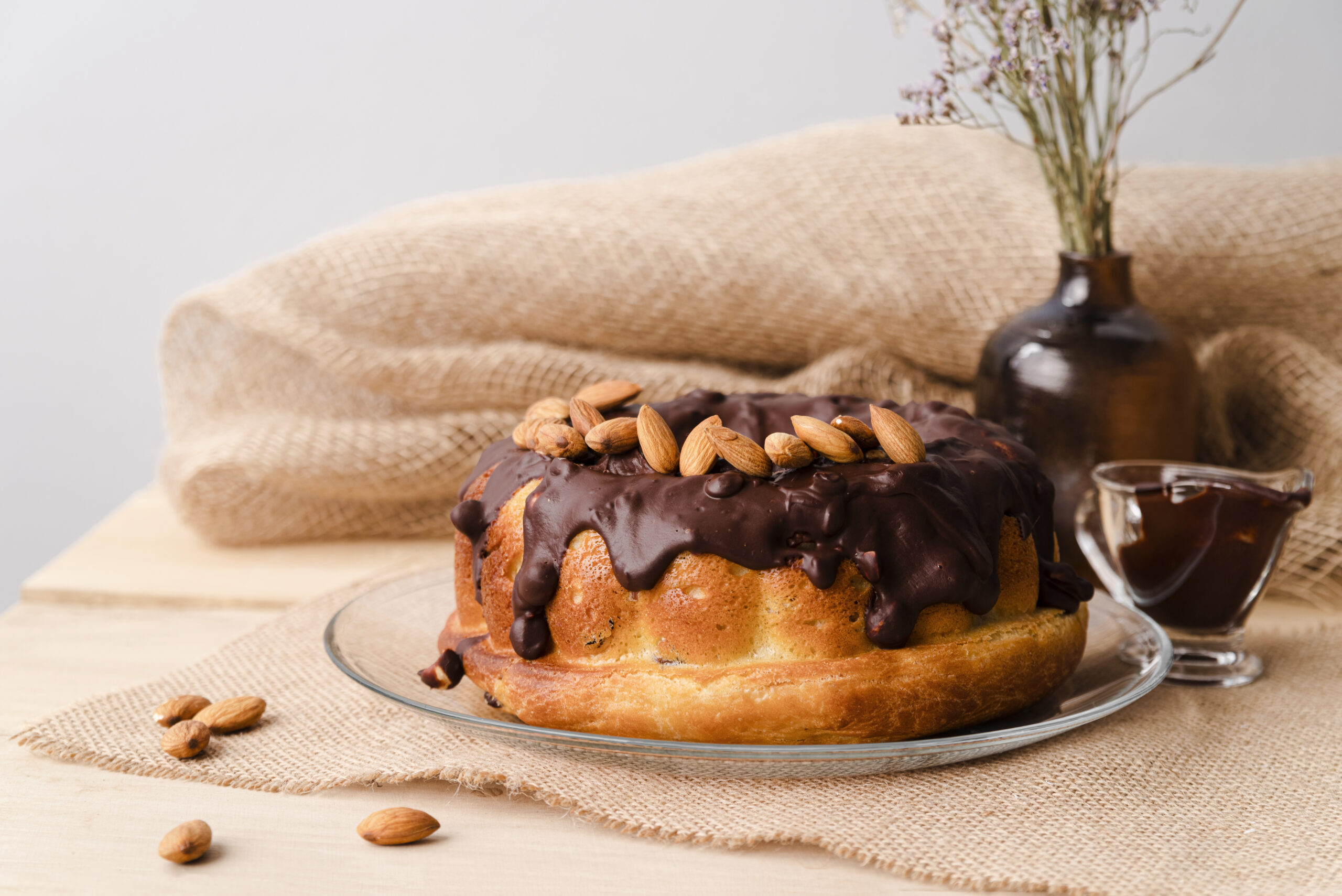 Bolo low carb de amêndoas com cobertura de chocolate e amêndoas inteiras por cima.