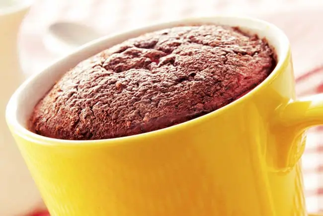 Bolo de caneca de chocolate recém-assado em uma caneca amarela.