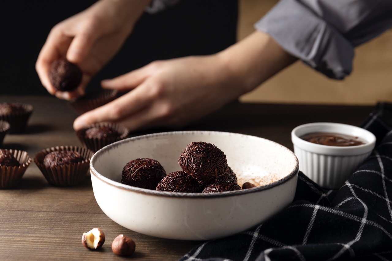 Mãos moldando brigadeiros cobertos com granulado de chocolate