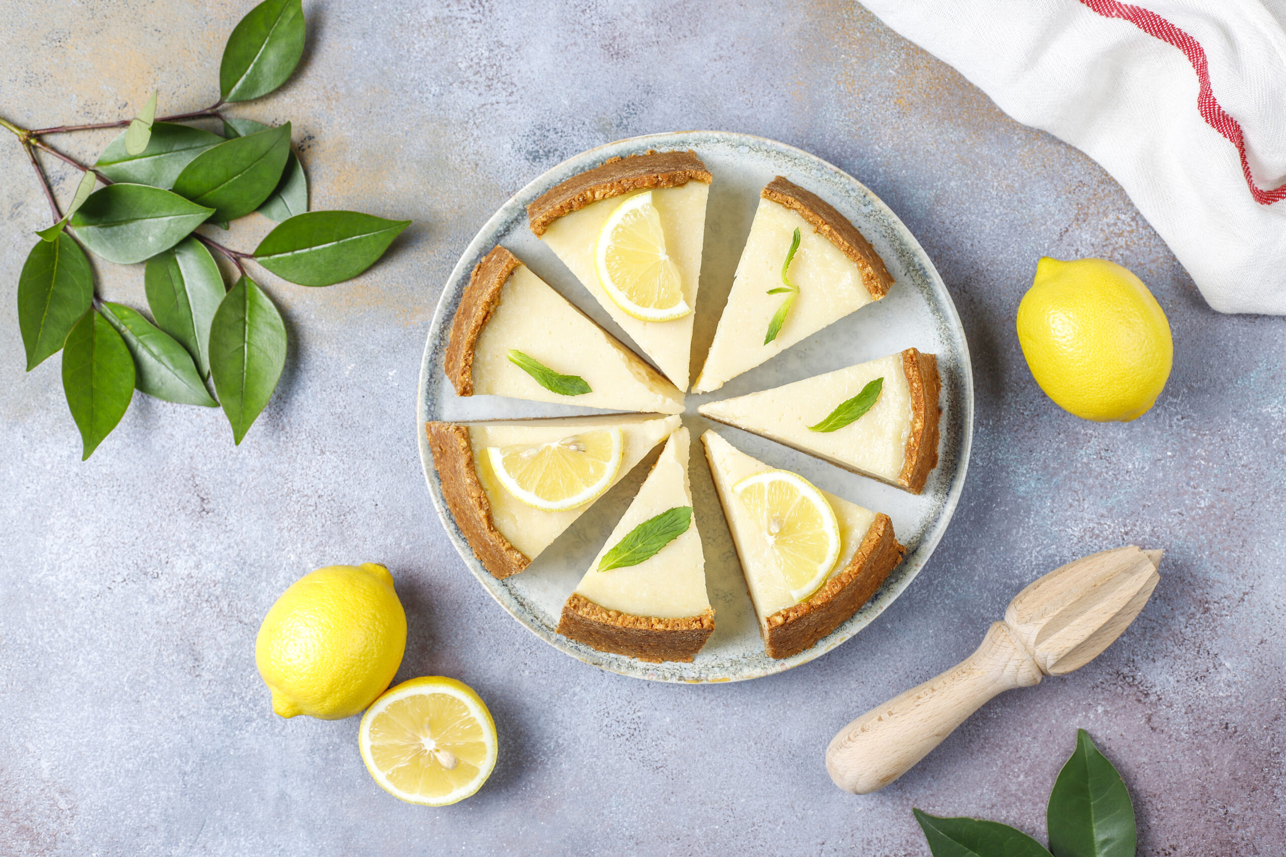 Cheesecake low carb de limão cortado em fatias e decorado com fatias de limão e folhas de hortelã.