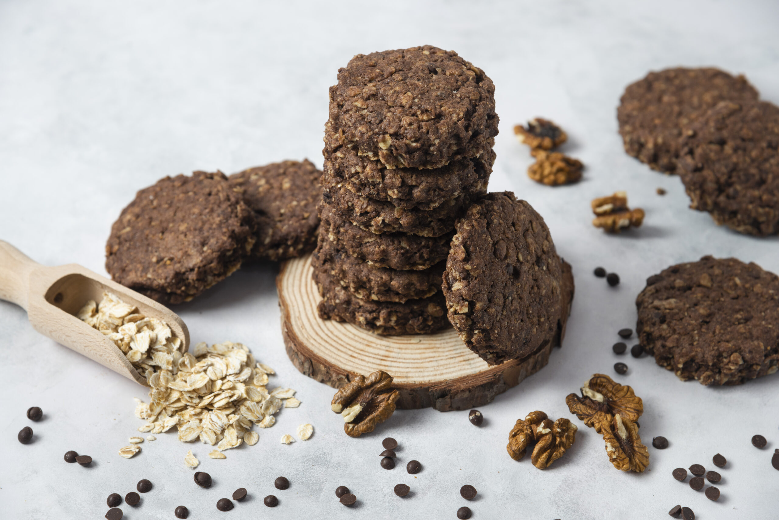 Cookies low carb de chocolate empilhados, com aveia e nozes ao redor.