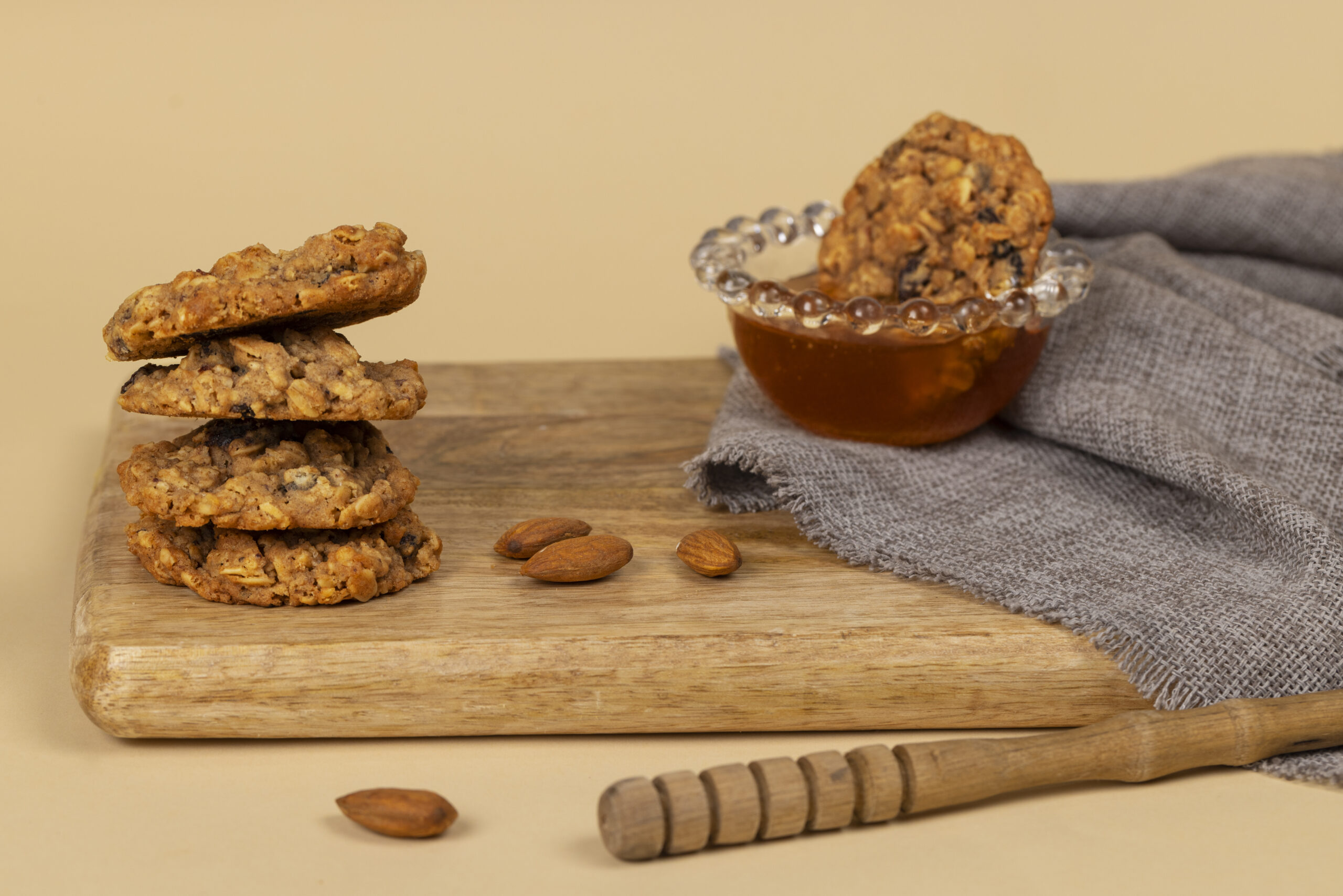Cookies de aveia e maçã para diabéticos dispostos em uma tábua de madeira, com amêndoas ao lado e mel em uma tigela.