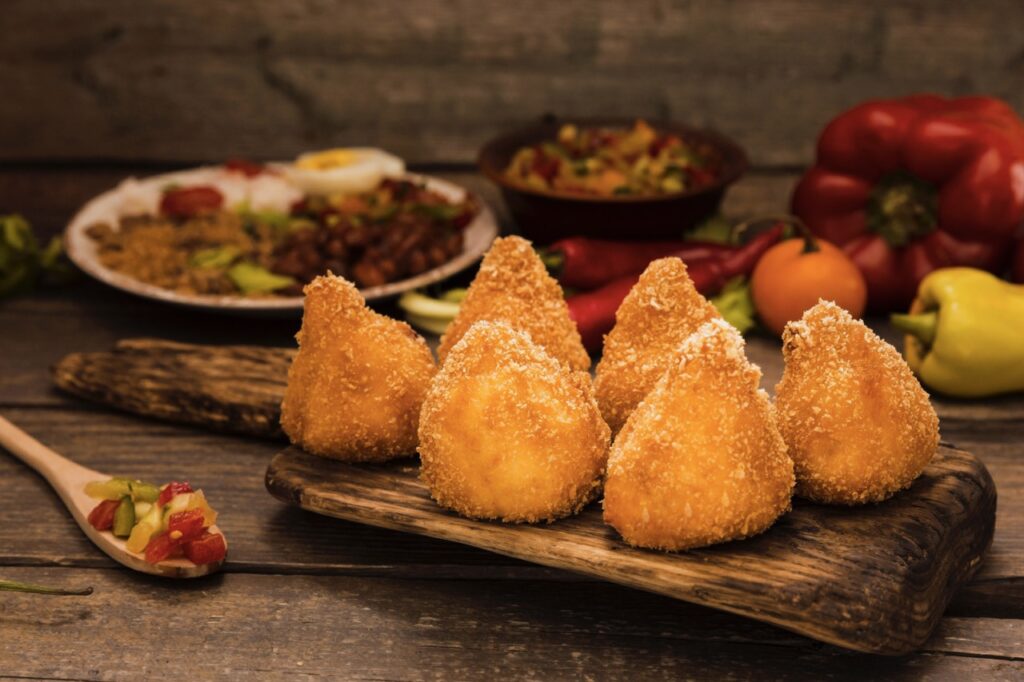 Coxinhas de frango empanadas servidas em uma tábua de madeira