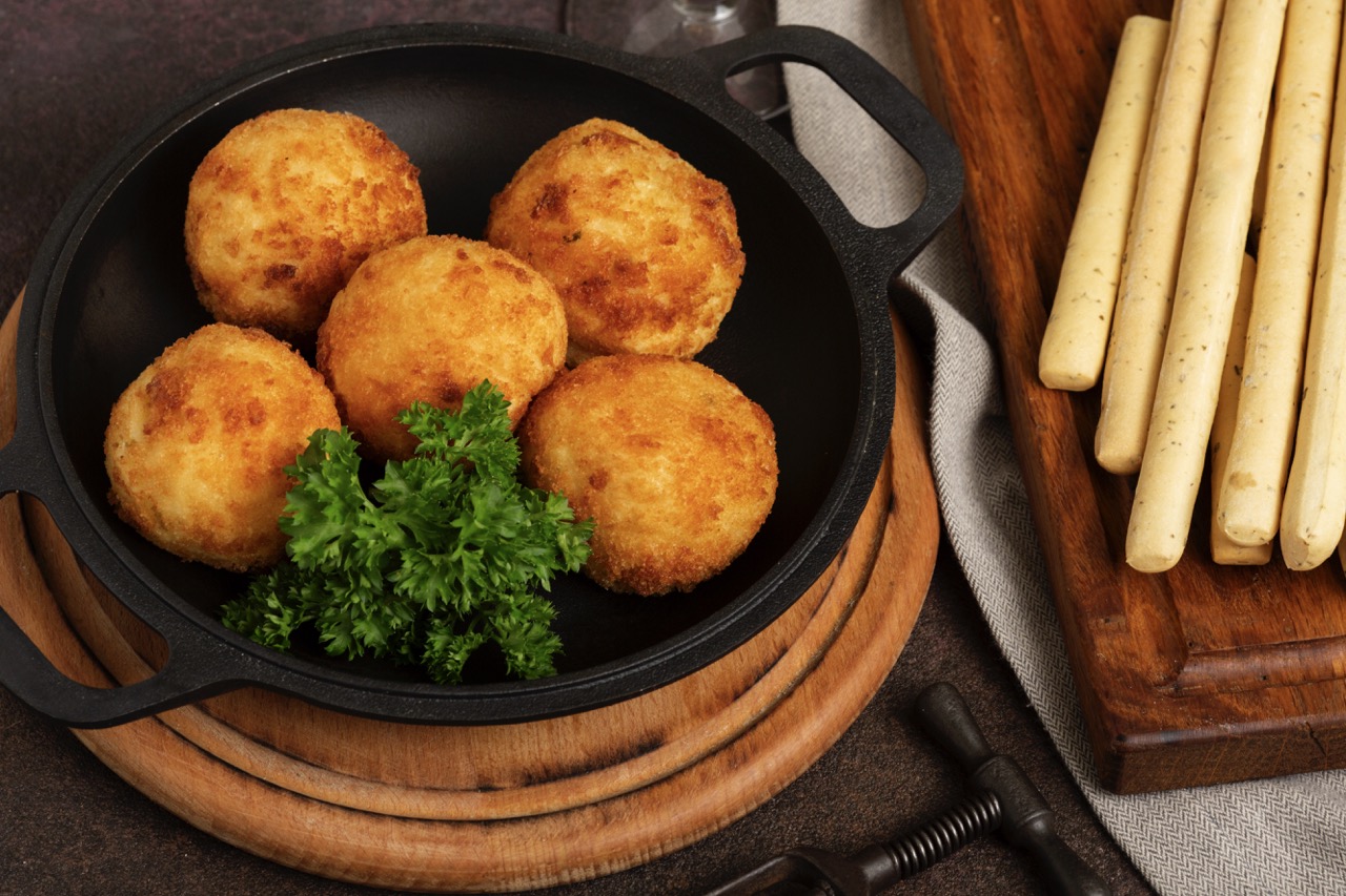 Coxinhas de frango crocantes preparadas na Air Fryer, acompanhadas de palitos de pão e decoradas com salsa fresca.