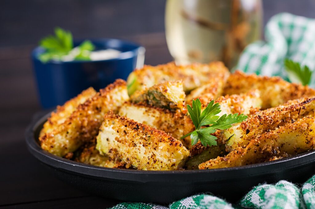 Prato de frango à milanesa crocante feito na Air Fryer, decorado com folhas de salsa fresca, servido em uma travessa preta com fundo desfocado, destacando uma textura dourada e crocante.
