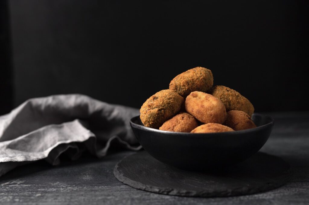 Almôndegas crocantes e douradas servidas em uma tigela preta, feitas na Air Fryer, perfeitas para uma refeição saudável e sem fritura.