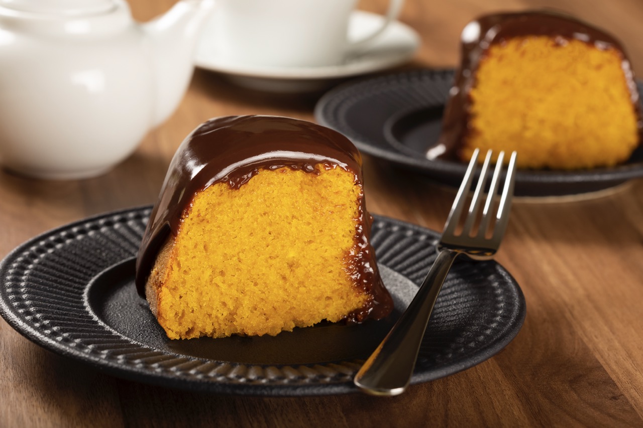Bolo de cenoura fofinho com cobertura de chocolate cremoso servido em prato preto.