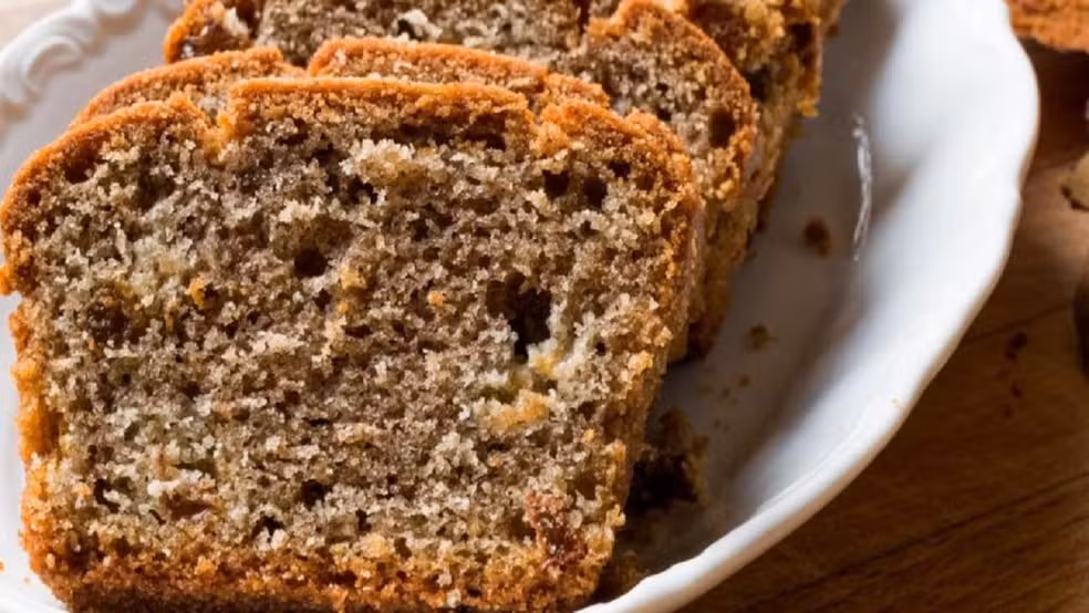 Fatia de bolo fit de banana com aveia e uva-passa, servido em prato.