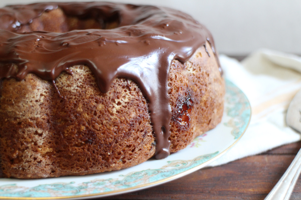 Bolo proteico de chocolate com whey coberto com calda de chocolate, servido em um prato decorado.