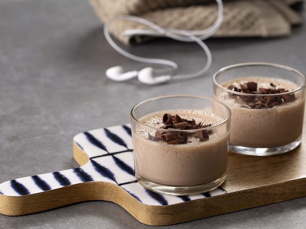 Mousse proteica de whey de chocolate servida em copos, decorada com raspas de chocolate.