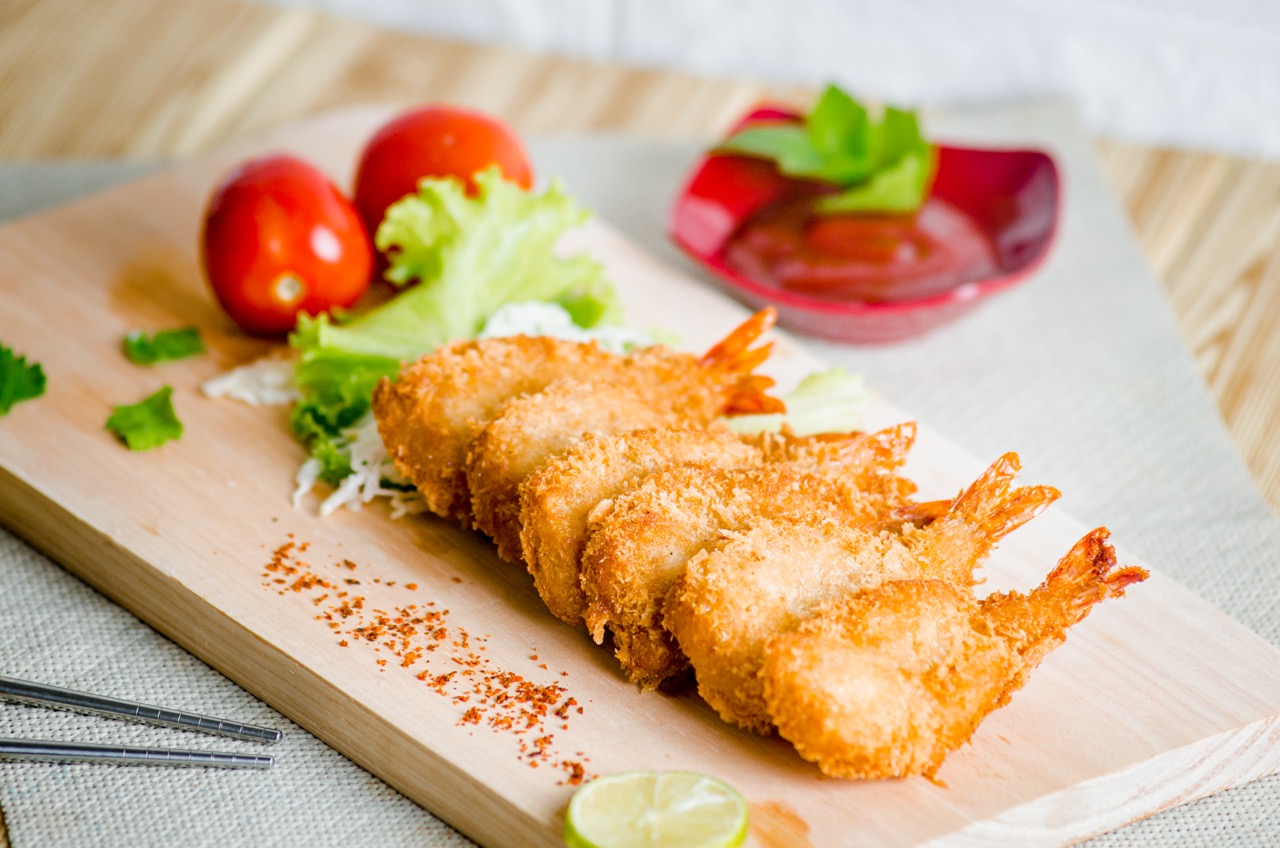 Filés de peixe empanados crocantes preparados na Air Fryer, servidos com alface, tomate e molho, destacando uma refeição saudável e sem fritura.
