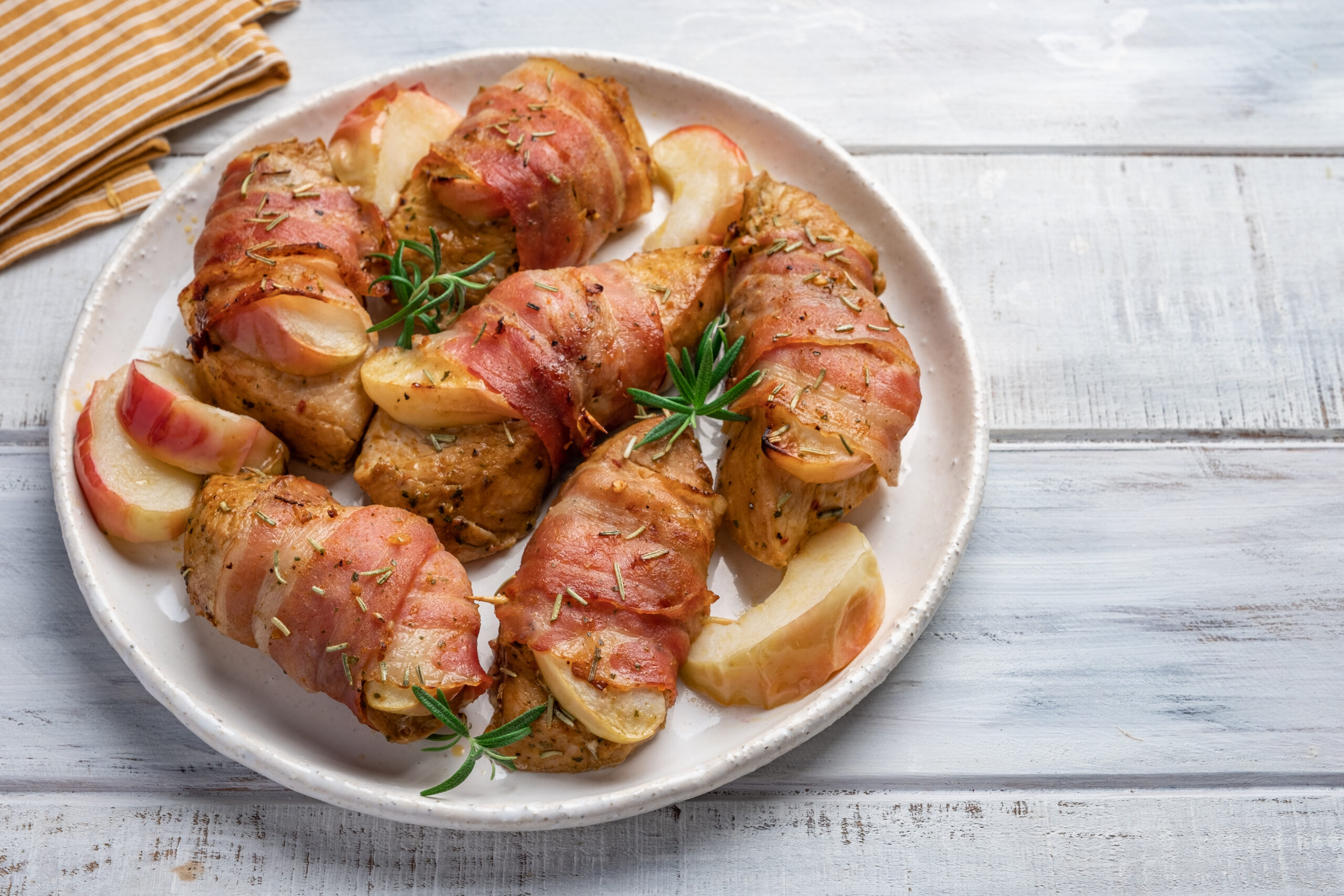 Frango enrolado com bacon e fatias de maçã em prato branco