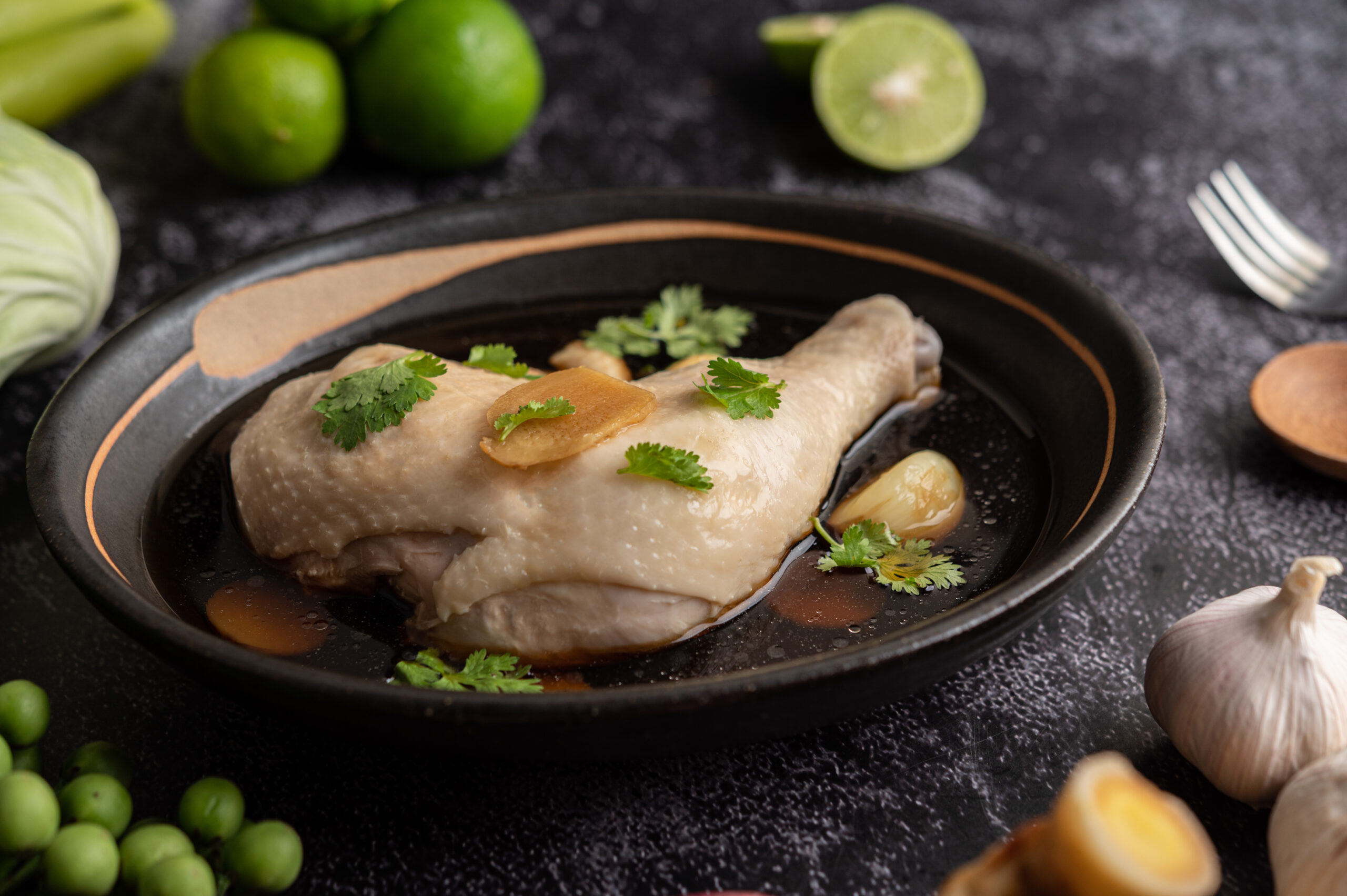 Coxa de frango suculenta com molho de mel e gengibre, decorada com alho, gengibre fatiado e folhas de coentro, servida em prato rústico.