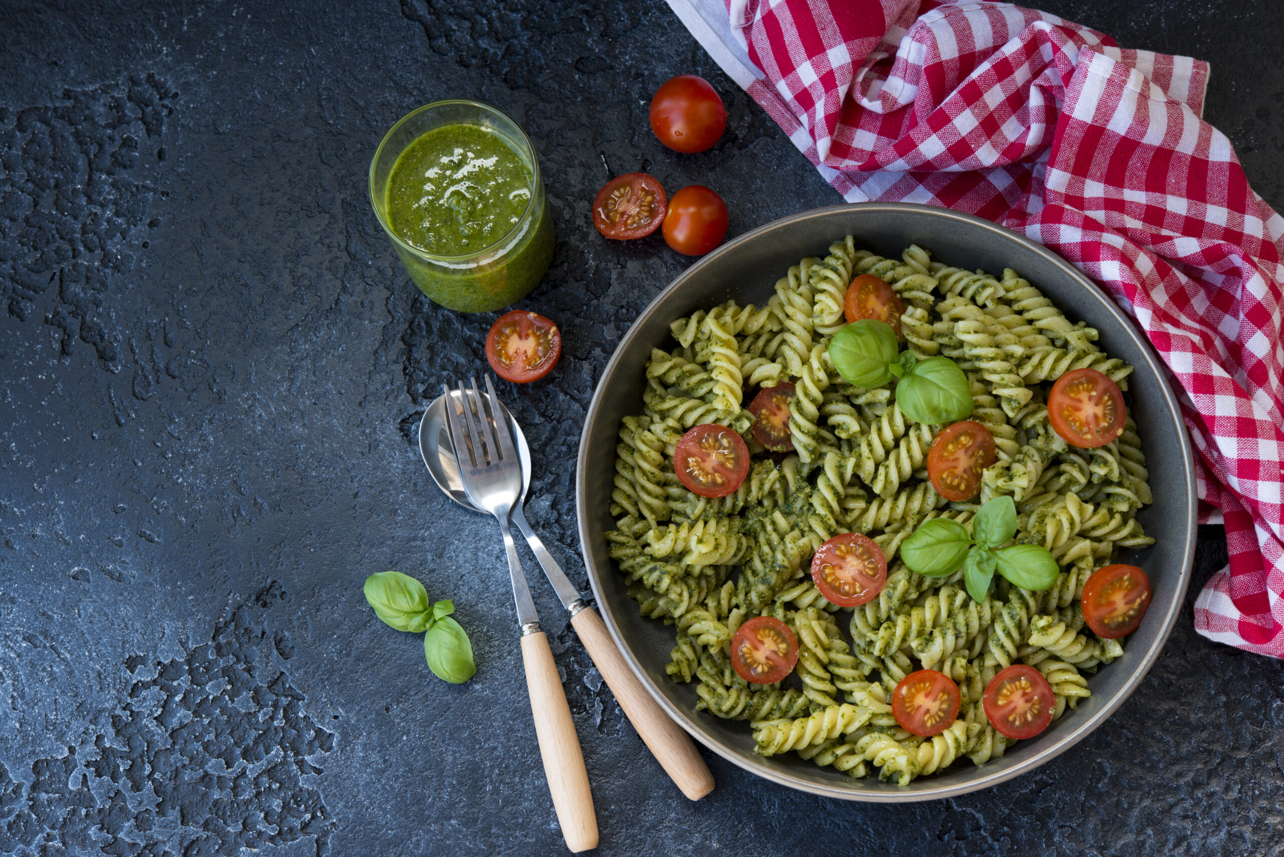 Salada de macarrão integral com pesto e tomates-cereja em uma tigela.