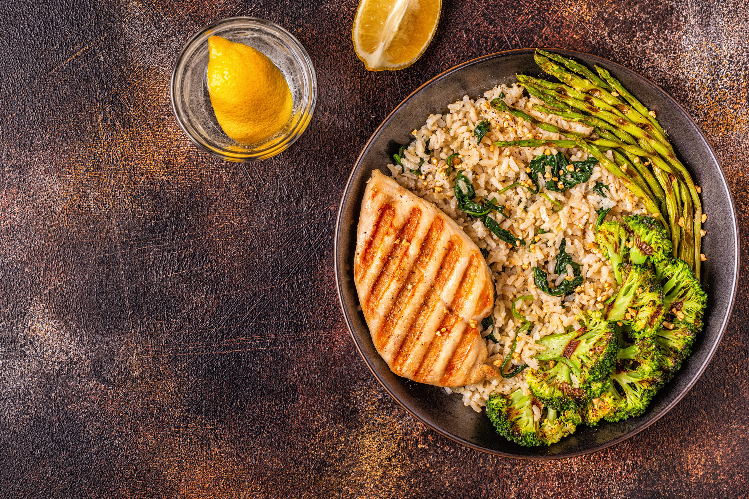 Prato de salmão grelhado com arroz integral, espinafre, brócolis e aspargos, acompanhado de limão.