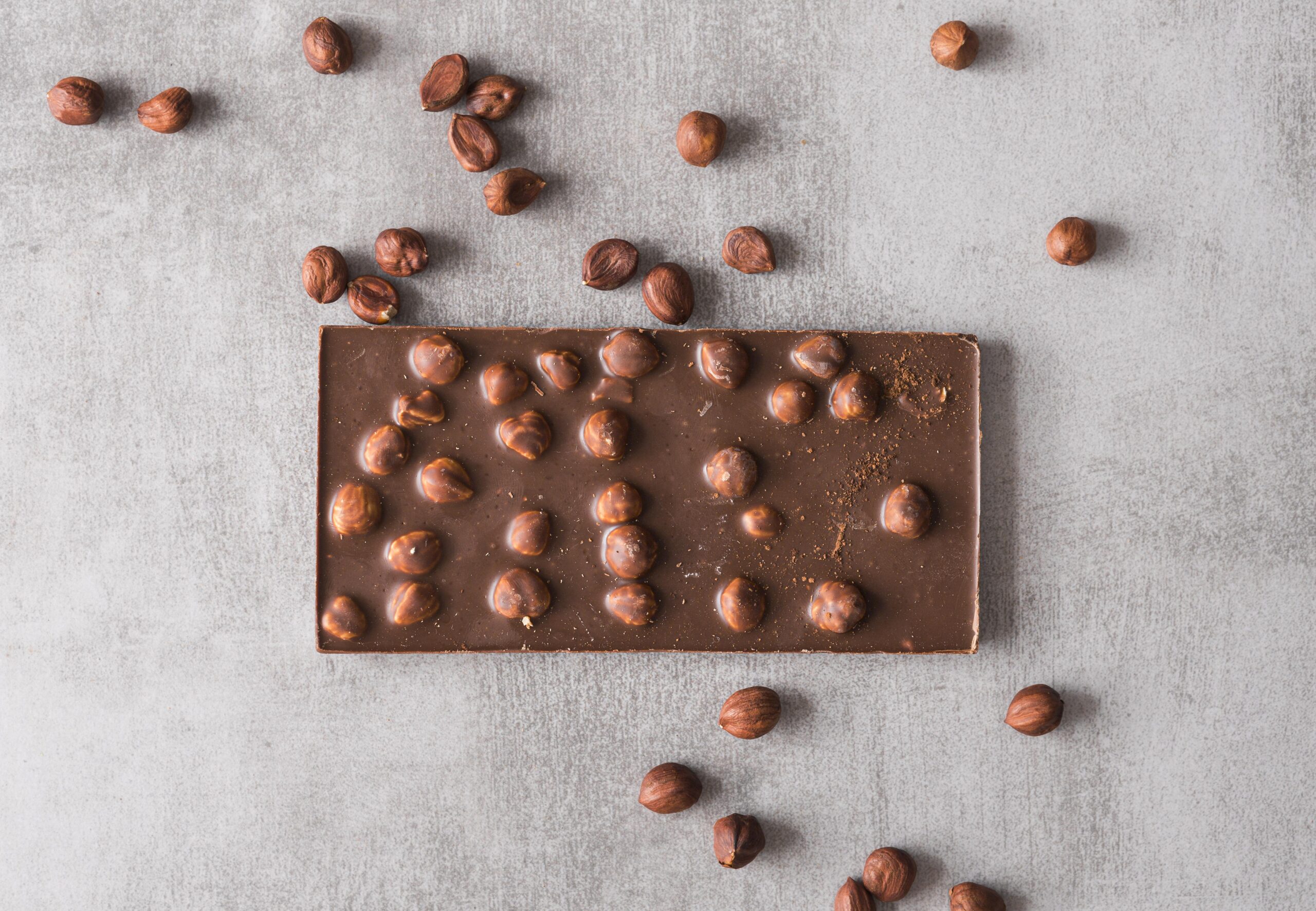 Barra de chocolate low carb com avelãs inteiras, sobre uma superfície clara, representando uma sobremesa saudável e nutritiva.