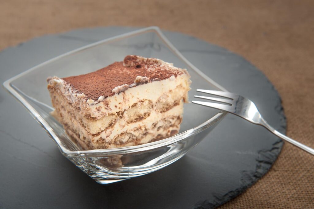 Fatia de tiramisù low carb com creme de mascarpone em um prato de vidro.