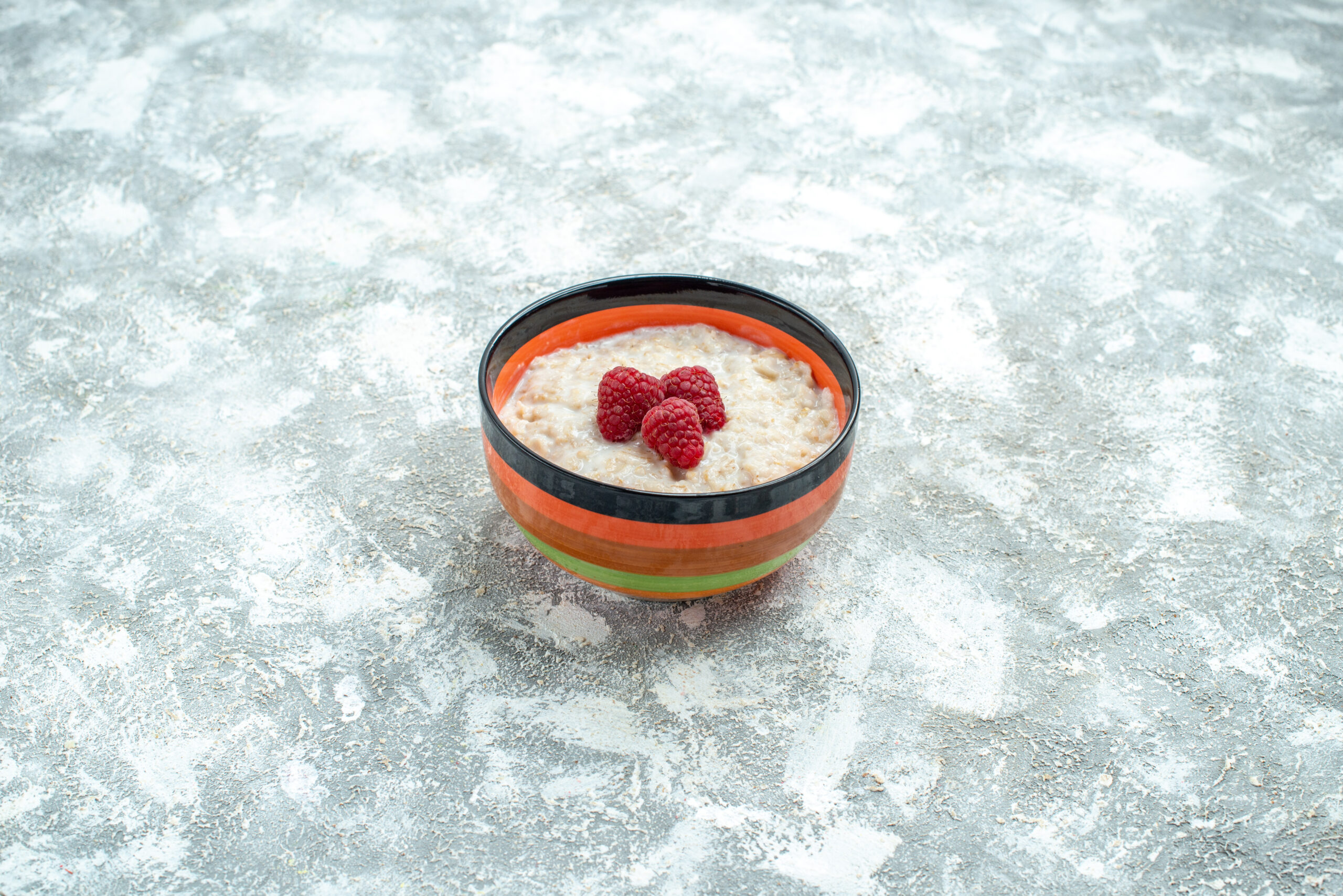Pudim de tapioca com whey decorado com framboesas frescas em uma tigela colorida.
