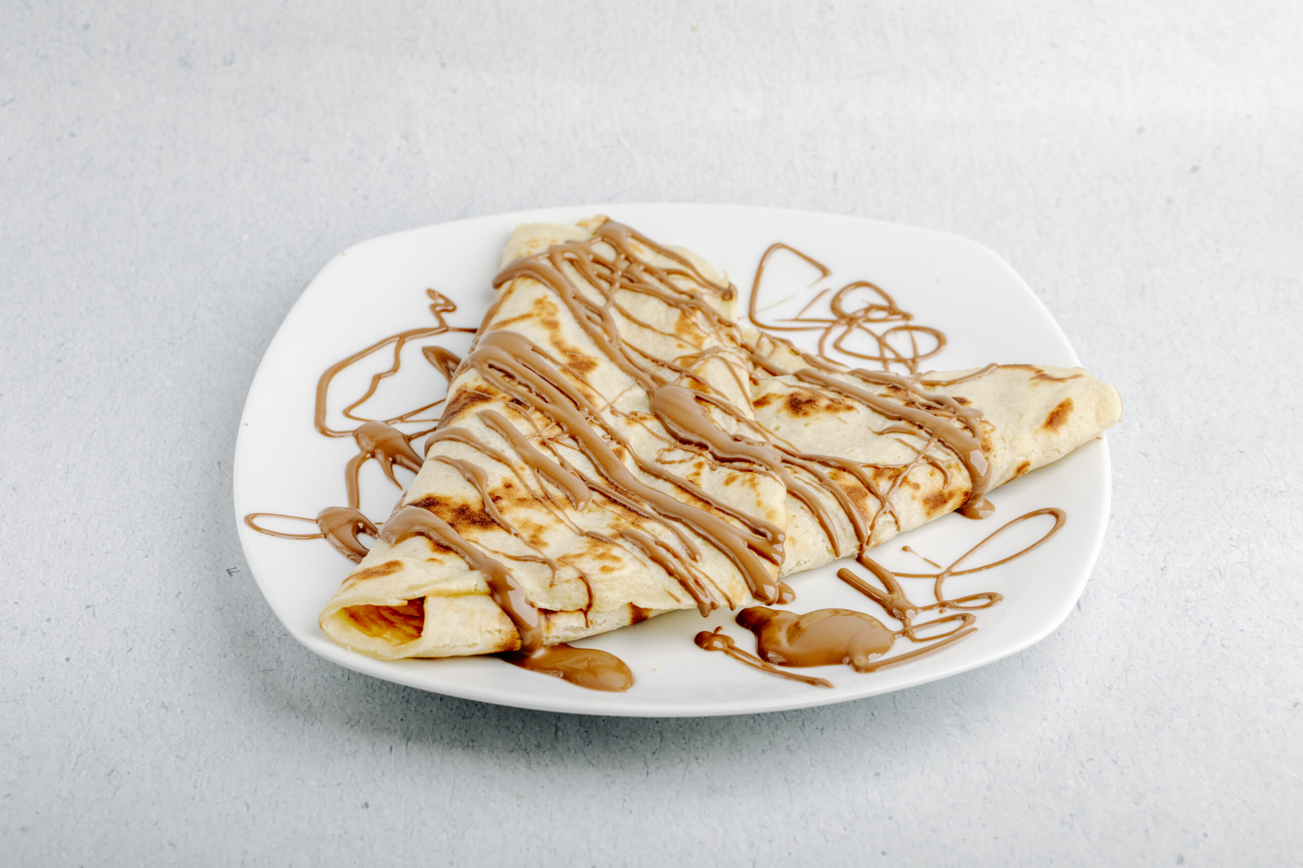 Crepe de aveia coberto com doce de leite diet em um prato branco.